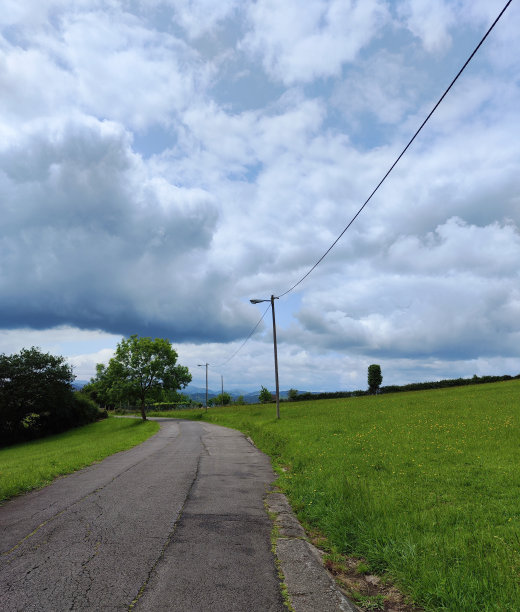 一条穿过绿色草地的道路的照片图片下载