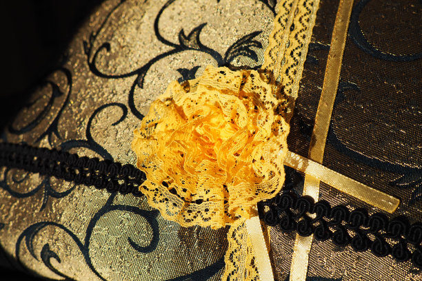 一个美丽的黄橙色花边人造花缝在一个装饰垫缎织物。蓝色密集的编织与薄聚酯花边。枕套的装饰。妇女的刺绣。图片下载