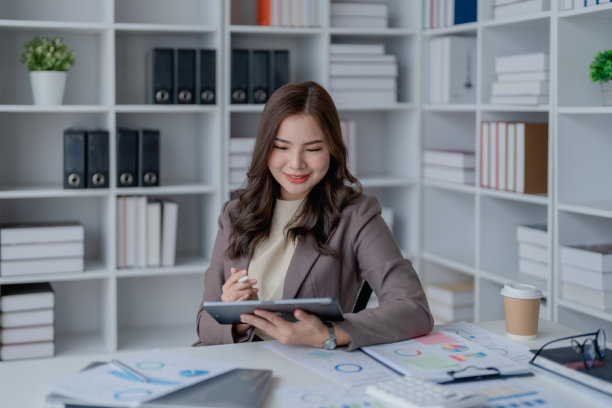 女商人穿着黑色西装，在办公室里用平板电脑，为客户联系审核文书，做生意的人概念。图片下载