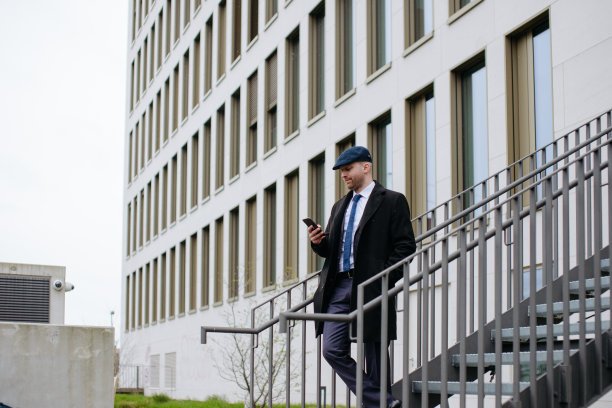 一个男人走下楼梯，看着他的手机图片下载