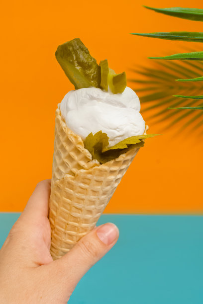 华夫蛋筒里夹着腌料和腌黄瓜的冰淇淋。美味的夏日甜点。不寻常的食物。素食食物。垂直照片与明亮的背景图片下载