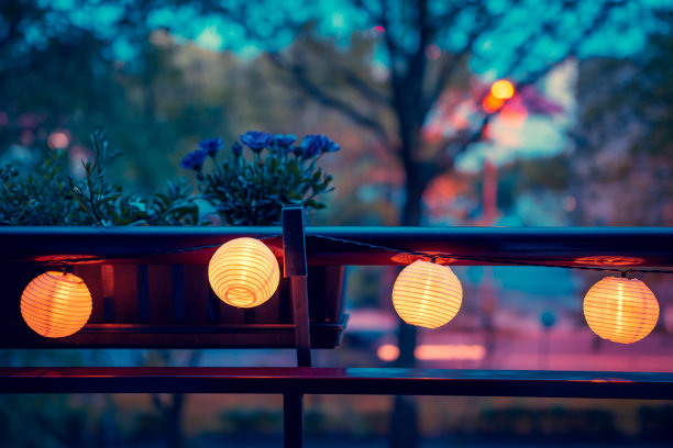 阳台的栏杆上挂着一个用太阳能灯点亮的花环。情绪。阳台花盆里的非洲雏菊。晚上好图片下载