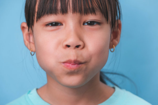 一个微笑的年轻女孩的特写，在蓝色的背景上露出她美丽的白牙齿。儿童健康的概念。图片下载