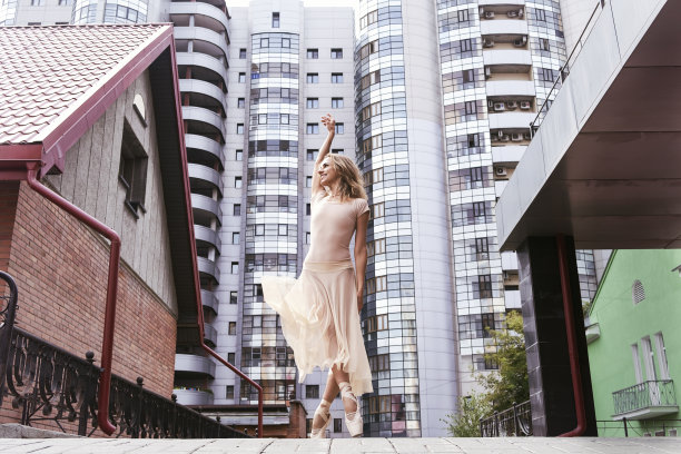 夏日里，一名芭蕾舞女演员在街上摆着足尖姿势，展示芭蕾舞的元素图片下载