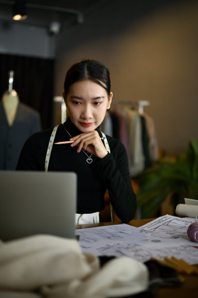 一位女时装设计师使用笔记本电脑，计划和设计她的新系列图片下载