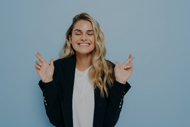 迷信的金发女学生双手交叉手指，祈求好运图片下载