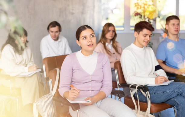 年轻的女学生在讲堂里聚精会神地听讲图片下载