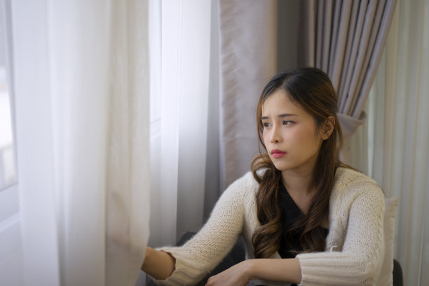 漂亮的女人带着悲伤的情绪坐在沙发上。图片下载