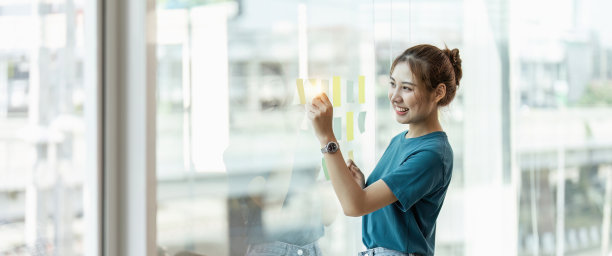 年轻的亚洲女性在便利贴上写文字分享想法。头脑风暴图片下载