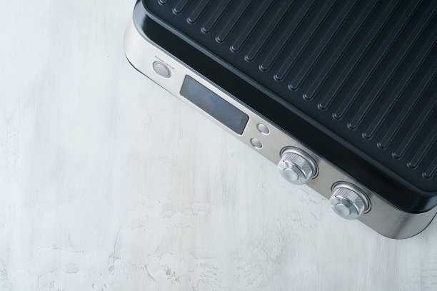 电动烧烤。现代厨房便携式烧烤工具为现代厨房烧烤肉类，蔬菜和零食的晚餐或聚会在浅灰色的背景。放文字或广告的地方。模拟。图片下载