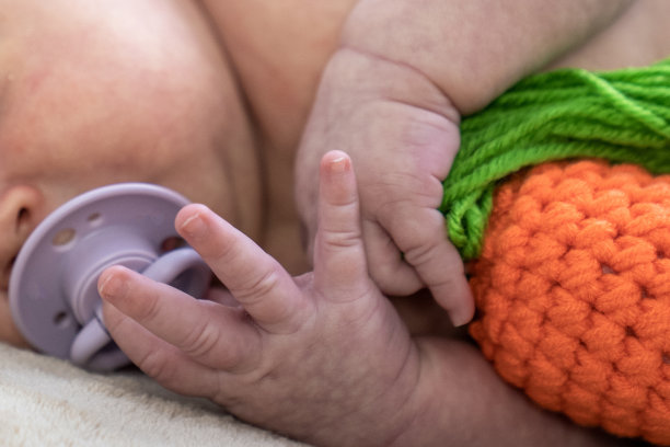 婴儿的小手指和手的特写，婴儿与安抚奶嘴和毛绒玩具图片下载