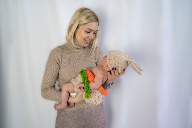 年轻女子爱的母亲抱着刚出生的婴儿在她的手中，家庭价值观，单亲与婴儿在针织手工服装图片下载