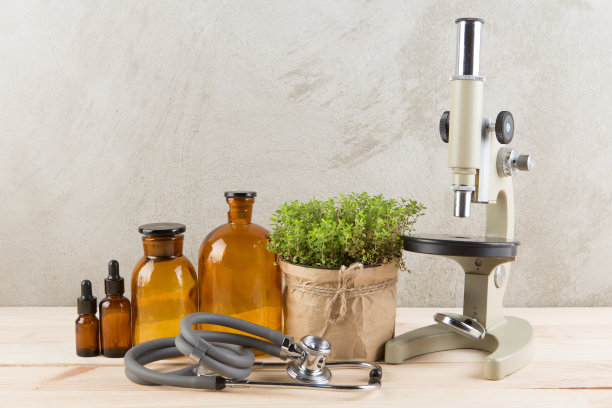 替代医学和植物学药瓶，草药，显微镜和听诊器在木桌上图片下载
