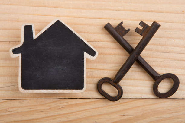 房地产：木质背景上的房屋模型与旧钥匙图片下载