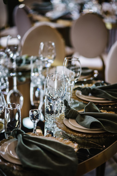 圆形宴会桌，有装饰的盘子，杯子，叉子，翠绿色的餐巾。优雅的餐桌。婚礼大厅装饰大气。金色几何装饰元素装饰。图片下载