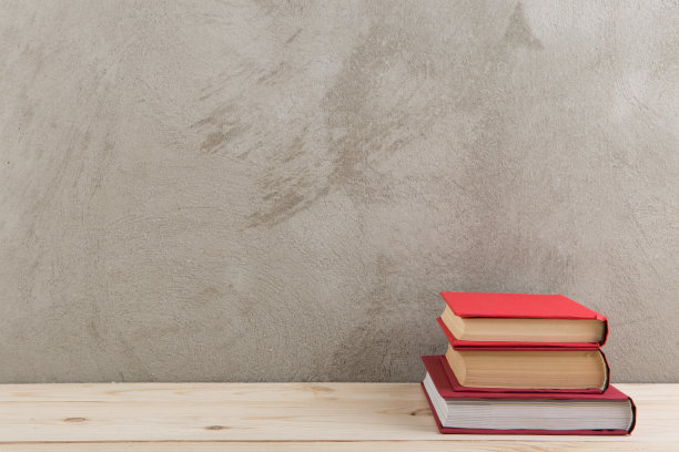 教育与阅读理念——木桌上五颜六色的成组书籍，水泥墙上的黑板图片下载