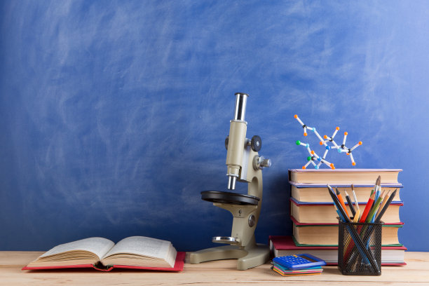 教育和科学的概念——礼堂的桌子上有书本、分子模型和显微镜，背景是黑板。图片下载