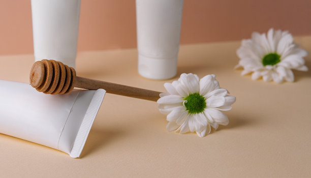 雏菊蜂蜜奶油。白色的瓶子化妆品。图片下载