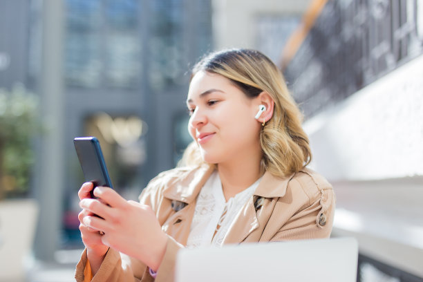 年轻女子在城市里使用无线耳机图片下载