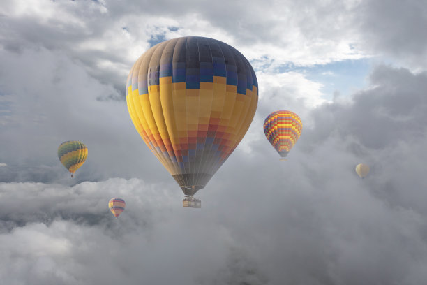 五颜六色的热气球在云层上飞行。图片下载
