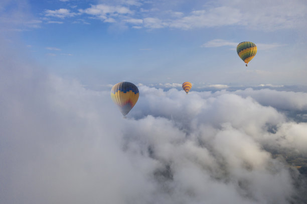 五颜六色的热气球在云层上飞行。图片下载