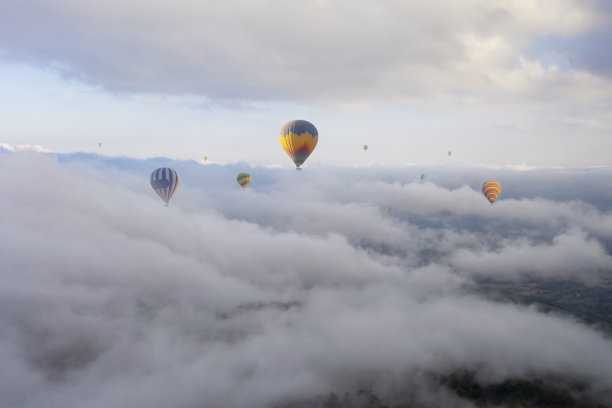 五颜六色的热气球在云层上飞行。图片下载