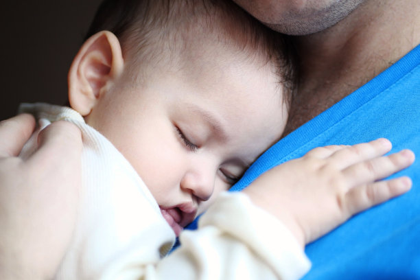 可爱的新生儿睡在父亲的怀里。一位慈爱的父亲在家里抱着她刚出生的孩子。一位快乐的母亲抱着熟睡的婴儿的画像图片下载