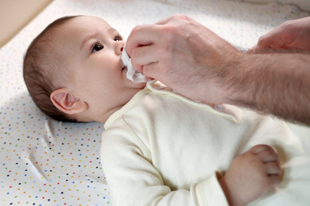 父亲用餐巾擦拭婴儿的嘴，她的小儿子用食物在家里(特写)图片下载
