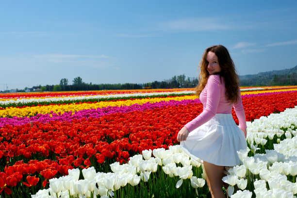 女孩在田间用郁金香纺纱风掀起裙子她弯下腰捧像玛丽莲梦露白色的花青春乐趣清洁发展头发谦虚克制清洁童贞图片下载