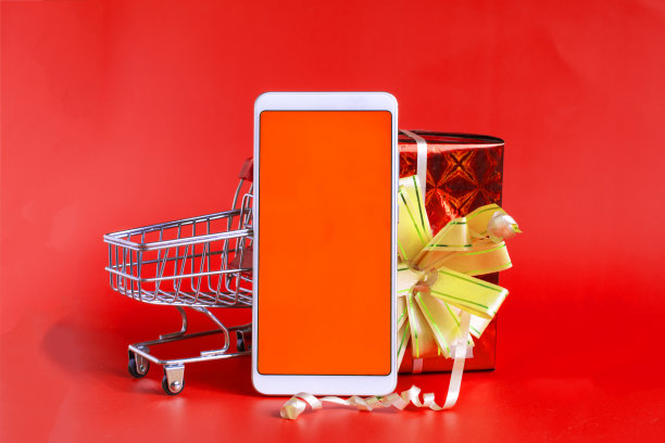 一个红色屏幕的手机，一个购物篮和一个红色背景的鲜红色包装里的礼物。图片下载