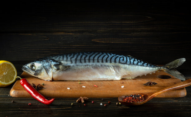 生烤鱼在厨房砧板上，用香料，胡椒和柠檬烹饪。免费广告位图片下载