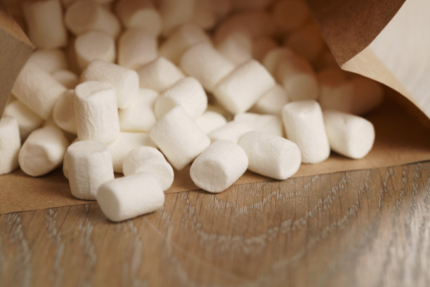 棉花糖装在棕色的工艺纸袋里，放在木桌上图片下载