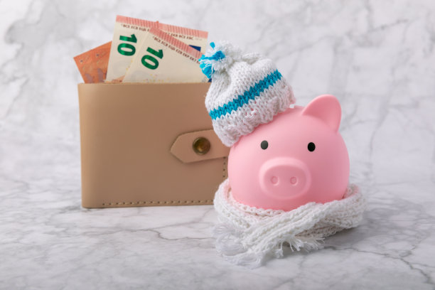 储蓄的概念。弹子桌上放着储蓄罐和钱。储蓄罐里的一顶暖冬帽，节约了热量。节热理念。放文字的地方。本空间图片下载