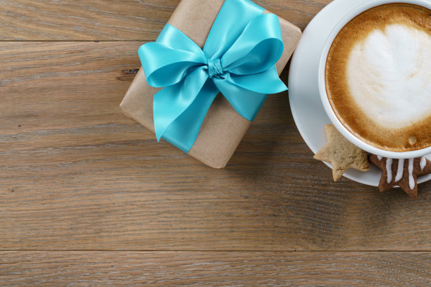 一杯卡布奇诺和礼盒与蓝丝带木制橡木桌面视图图片下载