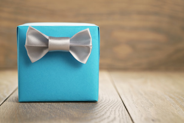 浅蓝色礼盒与极简主义的银丝带蝴蝶结上的木头图片下载