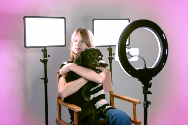 漂亮的网红女孩在色彩缤纷的工作室里拥抱她的狗。图片下载