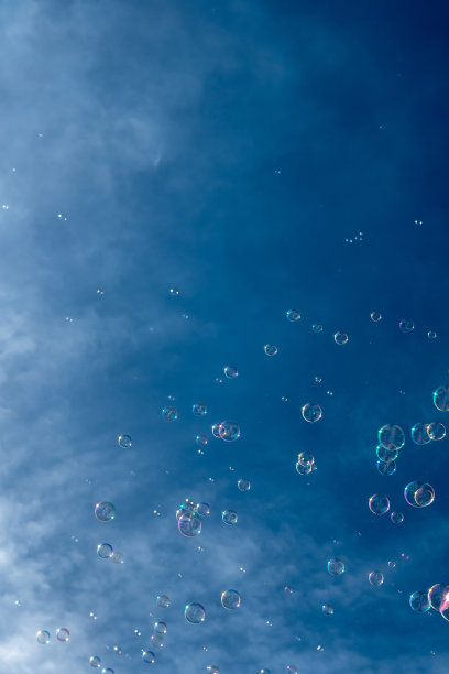 无数的彩色肥皂泡漂浮在蓝天前的半空中图片下载