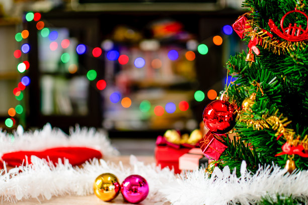 用小球茎装饰的绿色圣诞树是一种美丽的散景。圣诞树装饰用白色，红色，金色的球，特写一张照片，复制空间为设计，模糊木制背景。图片下载