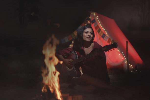 年轻的女孩在丛林里玩吉他，独自露营的照片图片下载