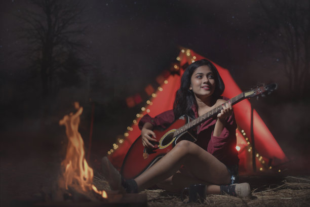 年轻的女孩在丛林里玩吉他，独自露营的照片图片下载