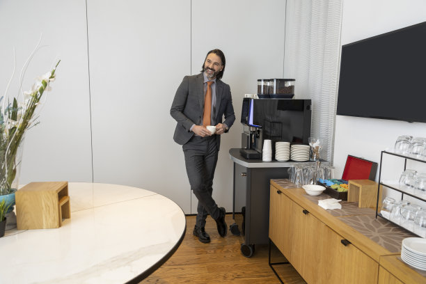 在办公室准备咖啡的商人，面带微笑图片下载