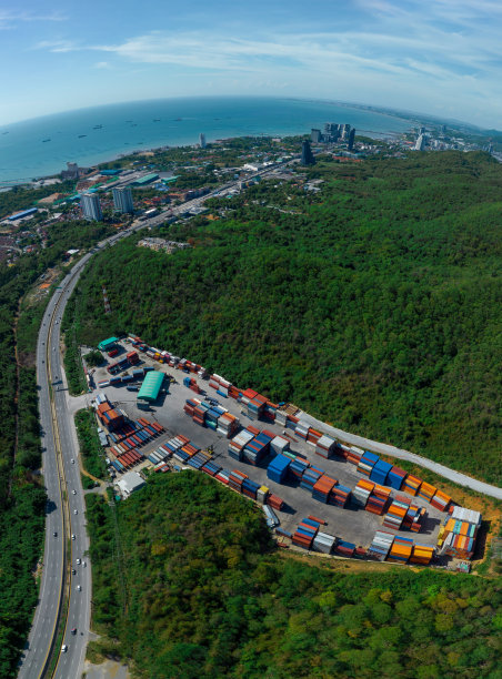 集装箱货场紧邻公路，四面环山，叉车和货物在堆场进行装卸运输，为客户提供概念物流快递服务图片下载