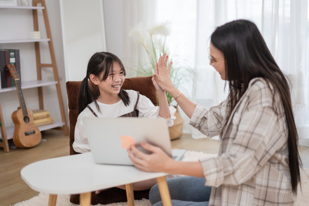亚洲家庭妇女和女儿击掌，一起使用笔记本电脑图片下载
