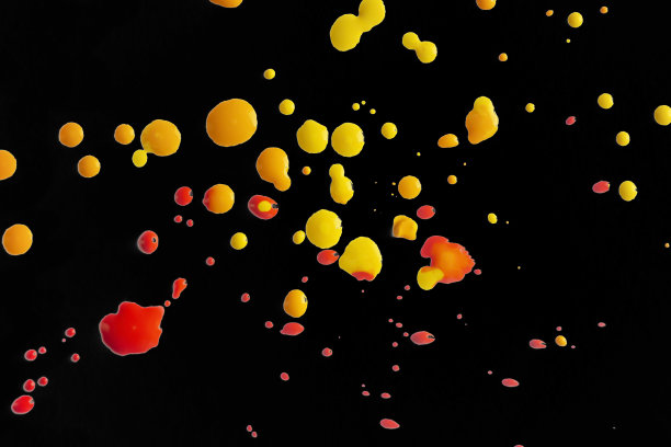 黑色背景上的黄色和红色斑点。黑色上的颜料飞溅。黑色画布上的颜料滴。图片下载