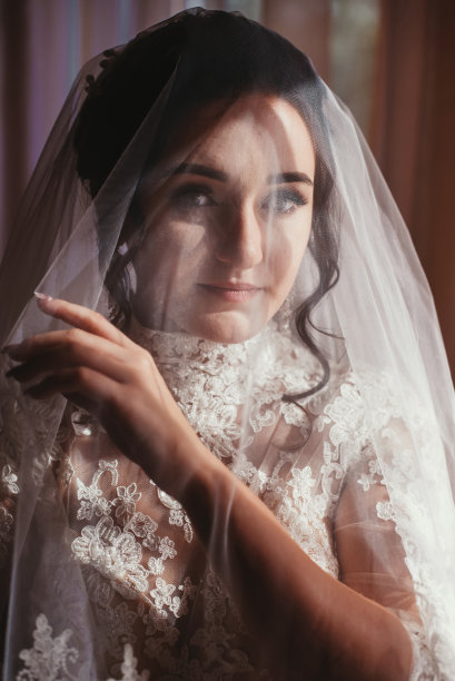 美丽的新娘肖像与面纱盖在她的脸上。年轻漂亮新娘的肖像。的婚礼。图片下载