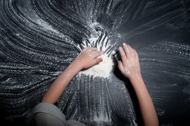 婴儿的手放在黑色的背景上，白色的粉末和面粉图片下载