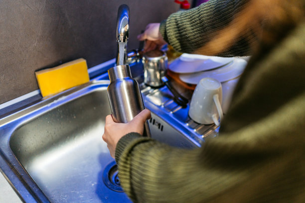 年轻女子把她的金属水瓶装满水图片下载