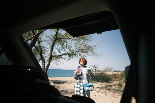 一个女人正把她的东西从汽车后备箱里拿出来，到山上的湖边休息图片下载