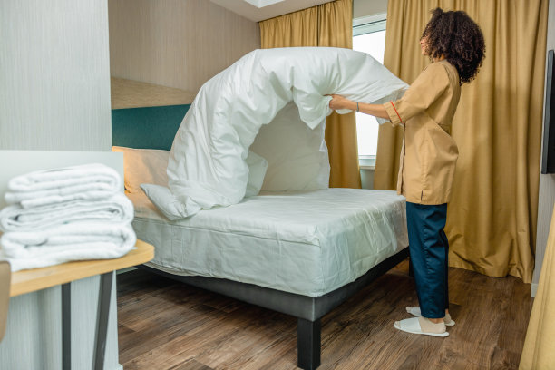 Young woman making bed in a hotel room图片下载