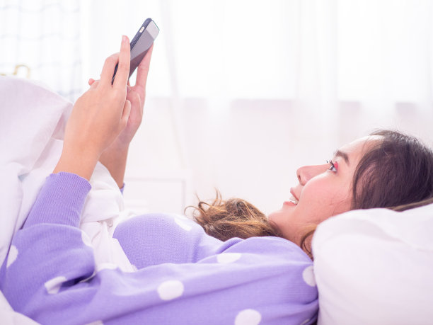 Woman lying in bed in the bedroom Relaxing playing online games and watch series Korea online with a smartphone During introvert, stay home and not going outside.图片下载